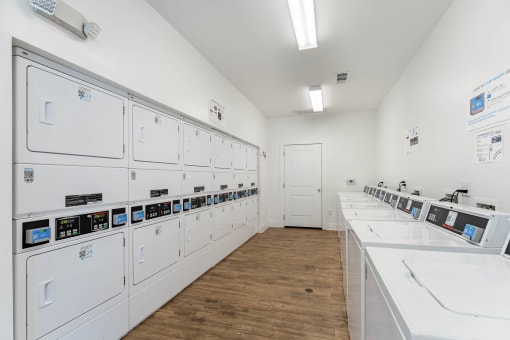a laundry room with white appliances and sinks and a door