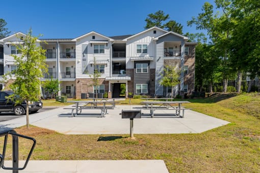 an outdoor picnic area with benches in front of an apartment building