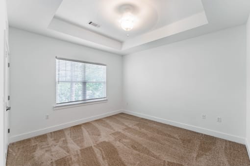 an empty living room with a window and white walls