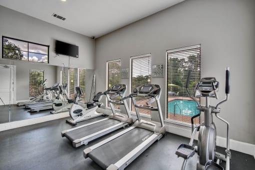 the gym with cardio equipment and windows overlooking the pool
