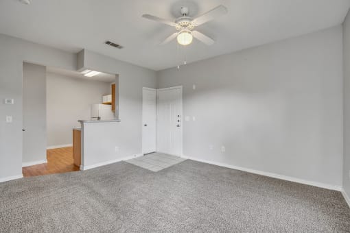 an empty living room with carpet and a ceiling fan