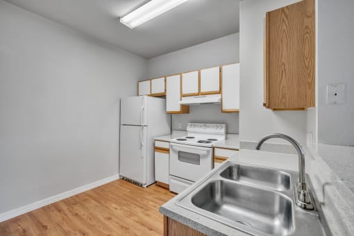 an empty kitchen with white appliances and wood flooring