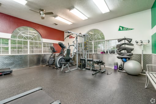 spacious gym with cardio equipment and windows at the enclave at woodbridge apartments