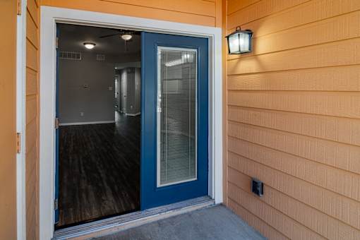 A blue door is open to a room with a light on the wall.