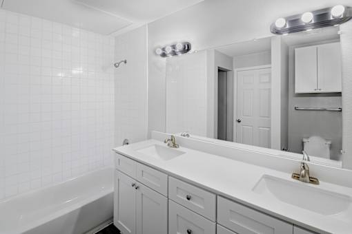 A white bathroom with a tub, sink, and mirror.