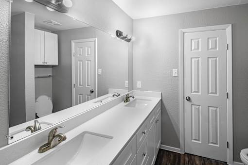 A bathroom with a white sink and a large mirror.
