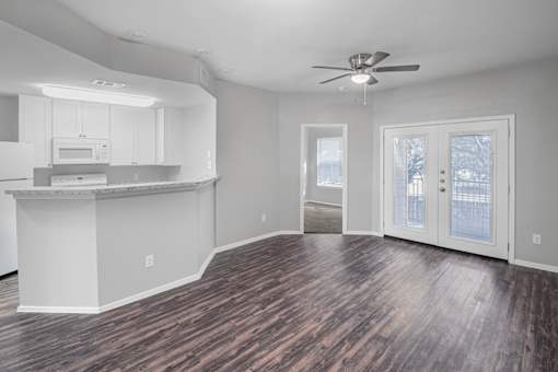 A spacious kitchen and living room with hardwood floors and white walls.