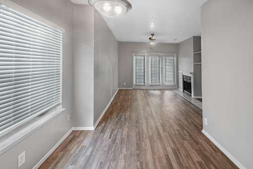 A room with wooden flooring and a window with blinds.