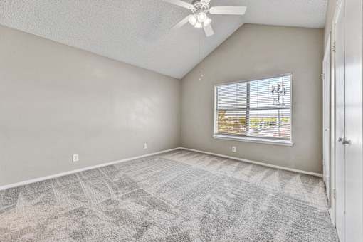 A room with a ceiling fan and a window with blinds.