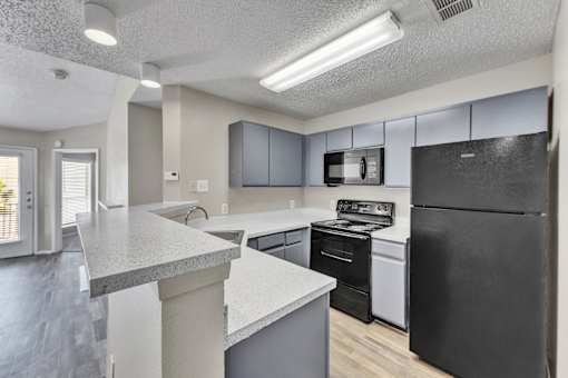 A kitchen with black appliances and a white counter.
