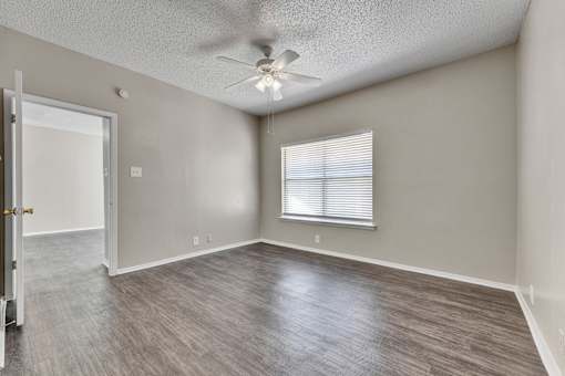 A room with a ceiling fan and a window with blinds.