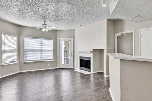A spacious living room with wood flooring and a fireplace.