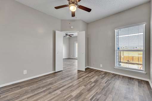 A room with a ceiling fan and a window with blinds.