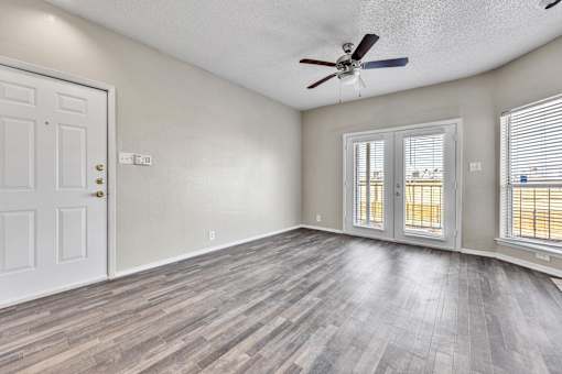 A room with a white door, a ceiling fan, and a window with blinds.