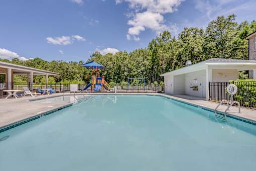 A large swimming pool with a slide and a house in the background.