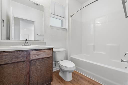 A white bathroom with a wooden vanity and a white bathtub.