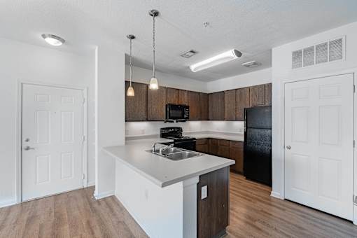A kitchen with a black refrigerator and wooden cabinets.