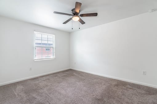 an empty room with carpet and a ceiling fan