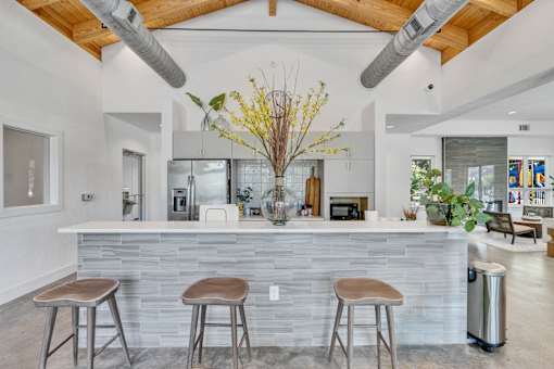 A modern kitchen with a stone counter and bar stools.