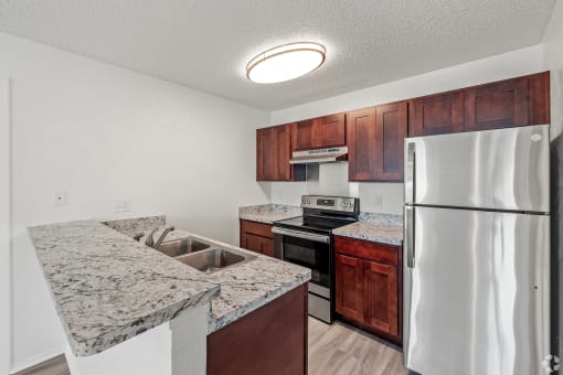 a kitchen with granite counter tops and a stainless steel refrigerator