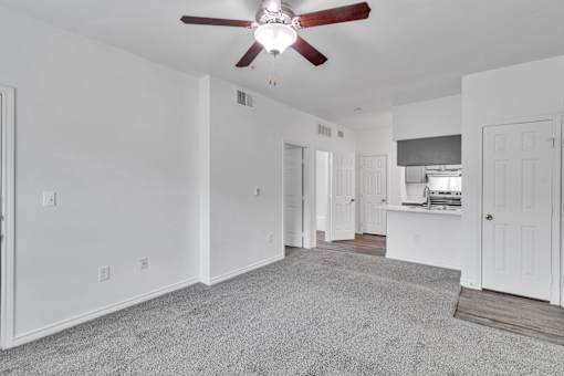 A room with a ceiling fan and carpeted floor.