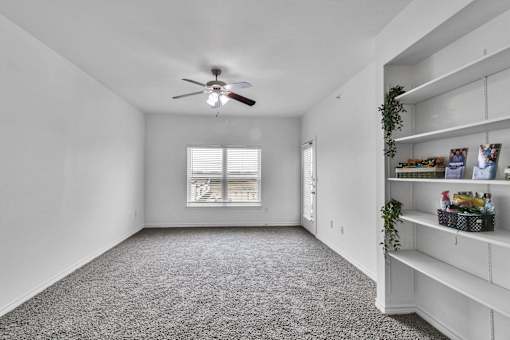 A room with a ceiling fan and a window with blinds.
