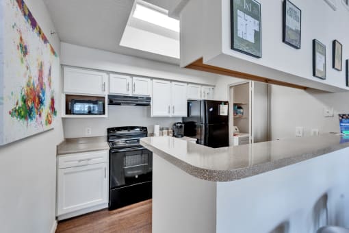 a kitchen with white cabinets and black appliances and a counter top