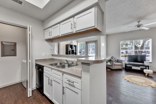 an open kitchen and living room with white cabinets and a counter top