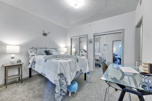 a bedroom with a bed and a glass desk