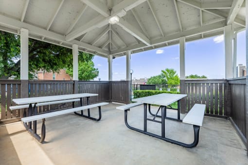 two picnic tables on a patio with benches
