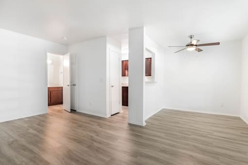 an empty living room with white walls and a ceiling fan