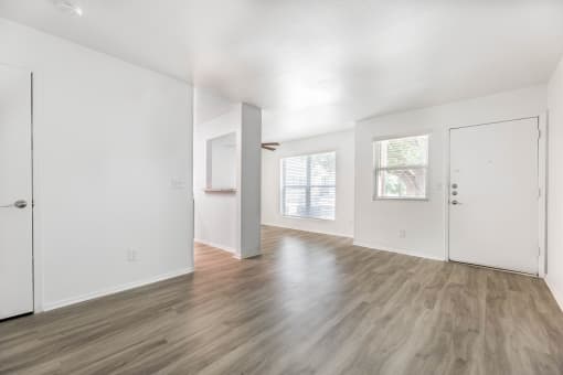 an empty living room with white walls and wood flooring