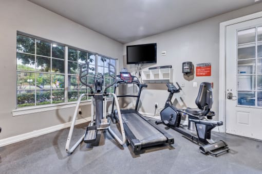 a gym with exercise equipment and a tv on the wall at Waters at Elm Creek, San Antonio, 78230