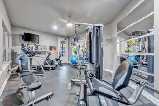 A gym with a variety of equipment including a leg press machine at Waters at Elm Creek, San Antonio