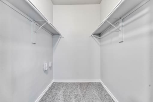 A white room with a grey floor and two white shelves on the wall at Waters at Elm Creek, San Antonio, Texas