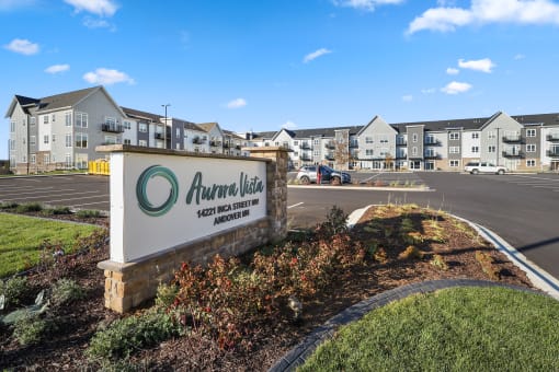 an apartment building with a sign in front of a parking lot