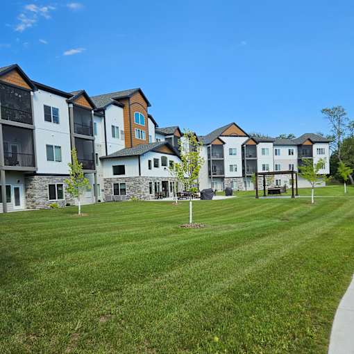 A row of multi-story apartment buildings with a grassy lawn in front.