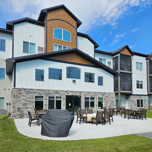 A modern house with a stone and wood exterior and a patio with furniture.