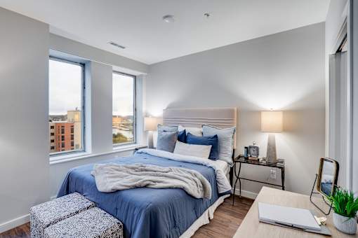 A bedroom with a large bed and a window overlooking a cityscape.