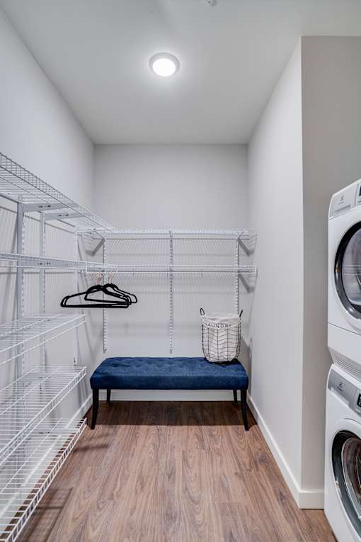 A laundry room with a bench and a washing machine.