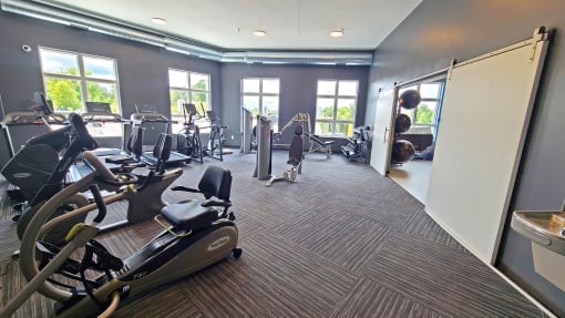 a gym with cardio equipment and windows in a building