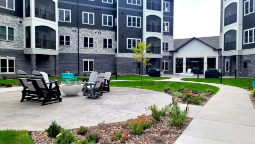 an outdoor patio with chairs and a table in front of an apartment building