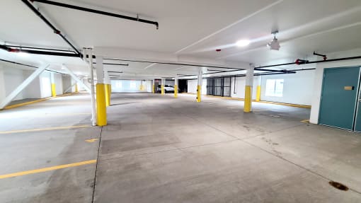 a parking garage with yellow pillars and a green door