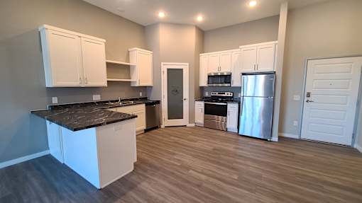 A kitchen with white cabinets and a black countertop.