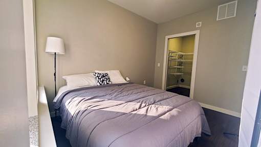 A bedroom with a bed, nightstand, and lamp.