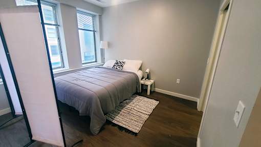A bedroom with a bed, nightstand, and window.