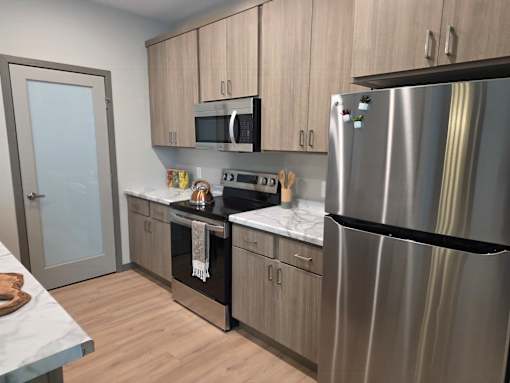 A modern kitchen with a stainless steel refrigerator, microwave, and oven.
