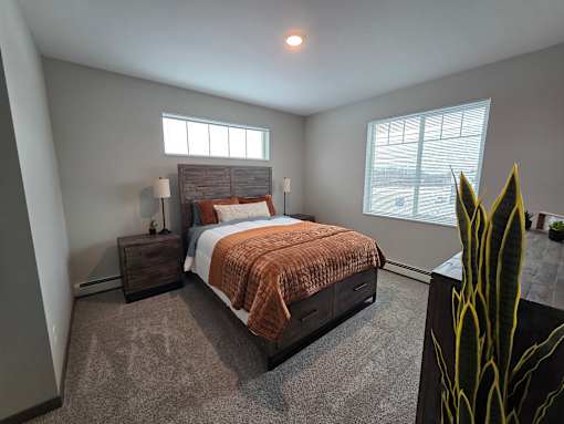 A bedroom with a bed, nightstand, and window.