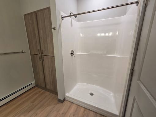 A white shower stall with a door and a shower head.