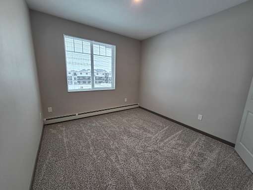A room with a window and carpeted floor.